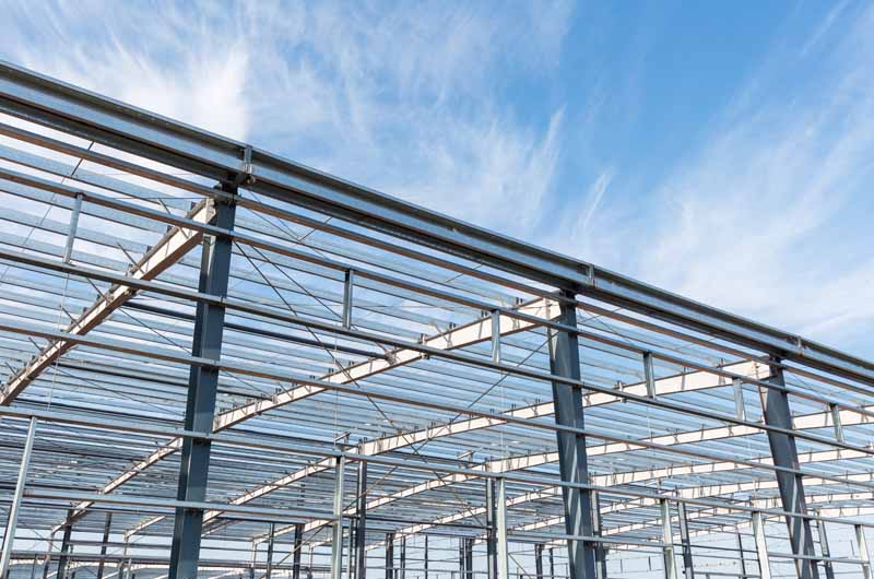 Steel structure under construction against a clear blue sky.